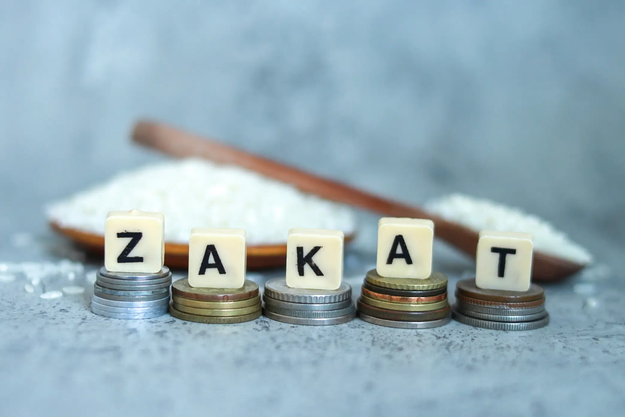 Ilustrasi zakat dengan huruf ZAKAT di atas tumpukan koin sebagai simbol keadilan sosial dan pemerataan ekonomi di Indonesia