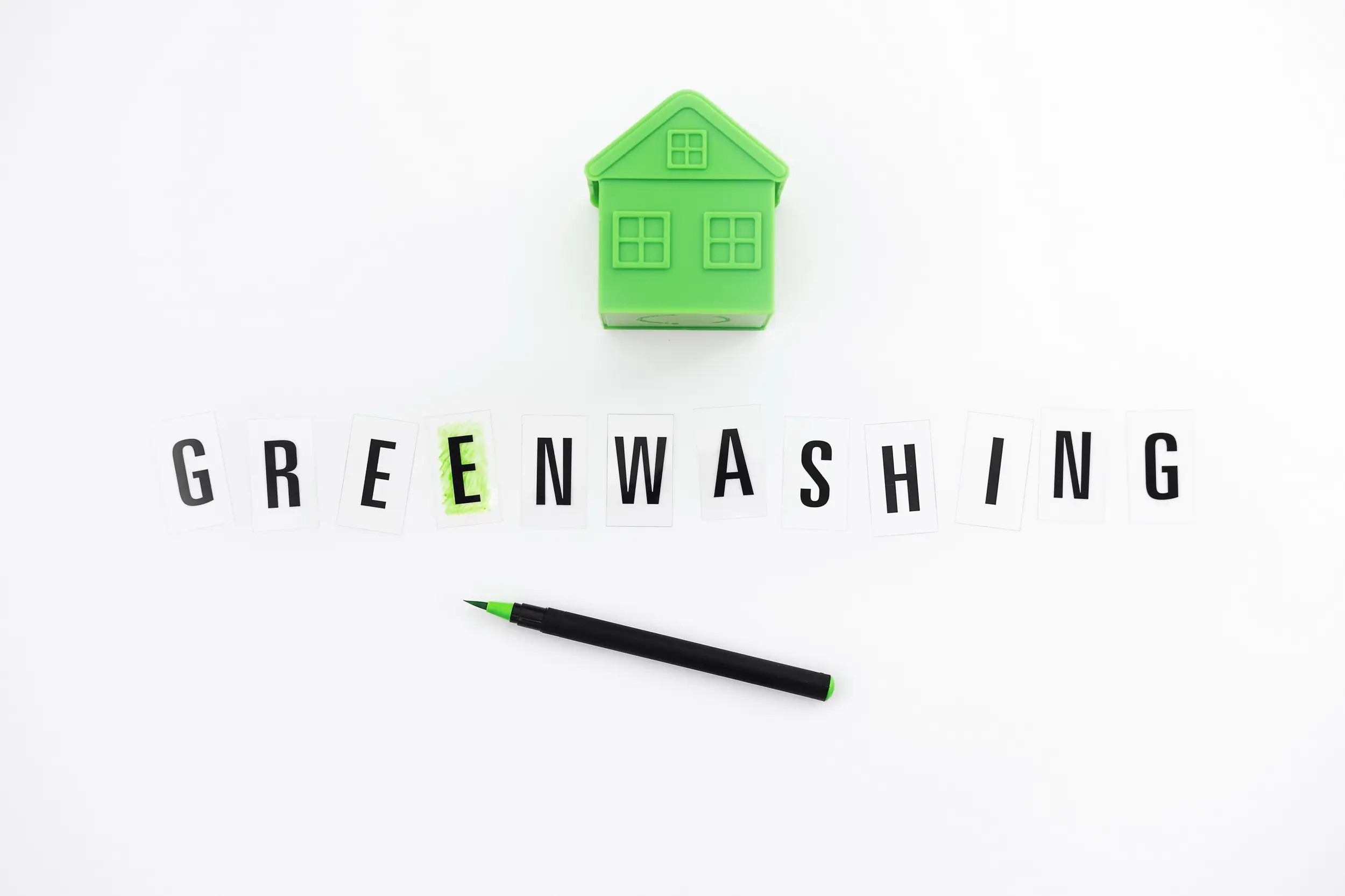 Greenwashing dengan ilustrasi rumah hijau dan tulisan greenwashing sebagai simbol klaim bisnis ramah lingkungan